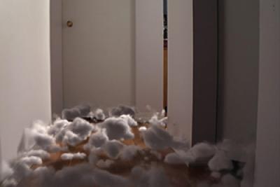Still from The Approach showing surreal cotton balls on the floor in the hallway of a house Still from The Approach showing surreal cotton balls on the floor in the hallway of a house