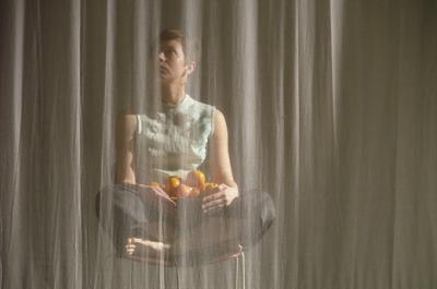 Wunderkammer woman cross legged behind curtain