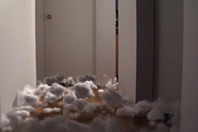 Still from The Approach showing surreal cotton balls on the floor in the hallway of a house Still from The Approach showing surreal cotton balls on the floor in the hallway of a house