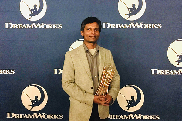 A photo of Lakshika Udakandage holding his Ingenuity Award from DreamWorks